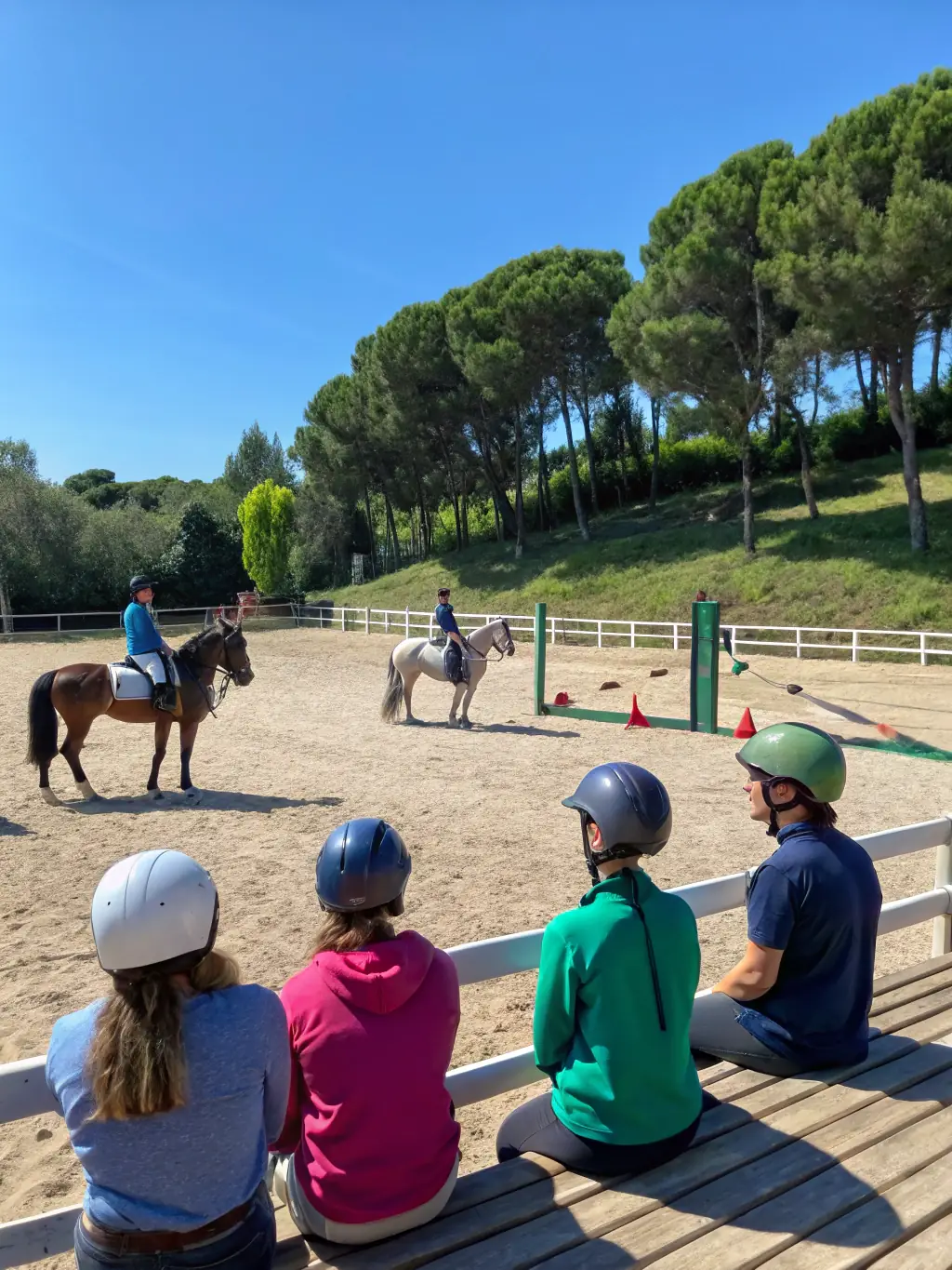 A group of riders participating in a training session in a scenic outdoor arena near Lac de Guerlédan, with lush greenery and clear skies in the background.